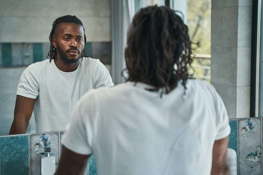 calm male concentrated on examining his face in bathroom